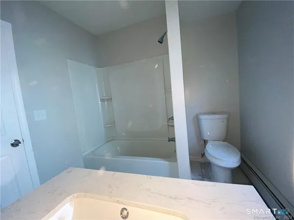 a bathroom with a granite countertop toilet and a shower