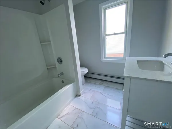 a bathroom with a tub a sink and a window
