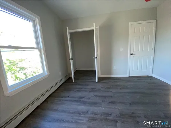 a view of hallway with window and wooden floor