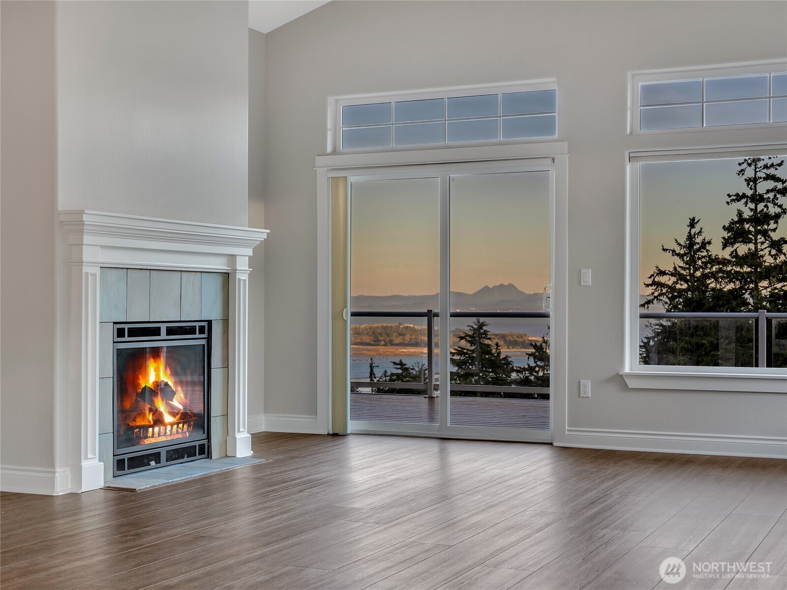 3224 Overlook Loop Ilwaco, WA 98624 - Photo 5 of 38 an empty room with wooden floor fireplace and windows
