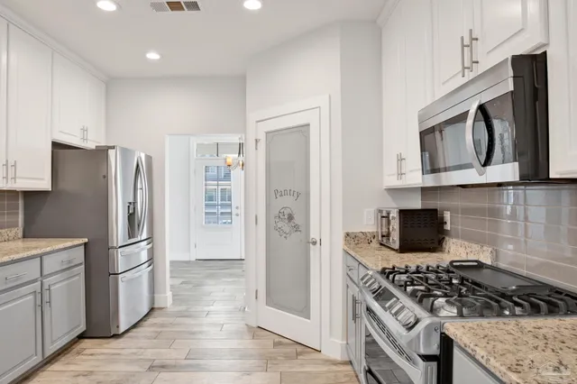 a large kitchen with stainless steel appliances granite countertop a sink and a refrigerator