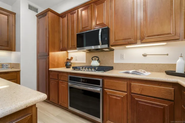 a kitchen with stainless steel appliances granite countertop a refrigerator a stove a sink dishwasher and white cabinets with wooden floor