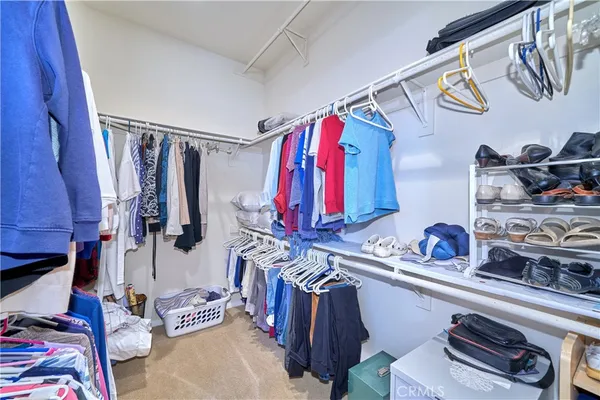 a view of walk in closet with clothes and shoes