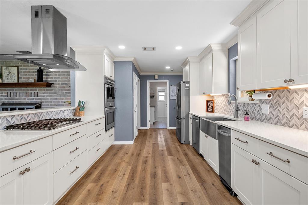 107 South Old Robinson Road Robinson, TX 76706 - Photo 12 of 39 Kitchen featuring island range hood, white cabinets, crown molding, stainless steel appliances, and light wood-style flooring