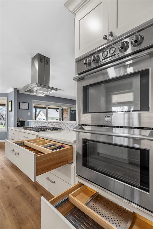 107 South Old Robinson Road Robinson, TX 76706 - Photo 14 of 39 Kitchen with stainless steel appliances, a warming drawer, island range hood, light wood-style flooring, and light countertops