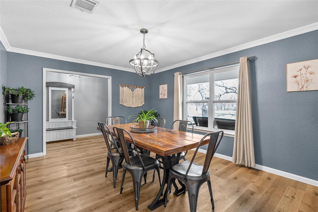 107 South Old Robinson Road Robinson, TX 76706 - Photo 16 of 39 Dining room featuring a textured wall, light wood finished floors, crown molding, and hanging lights