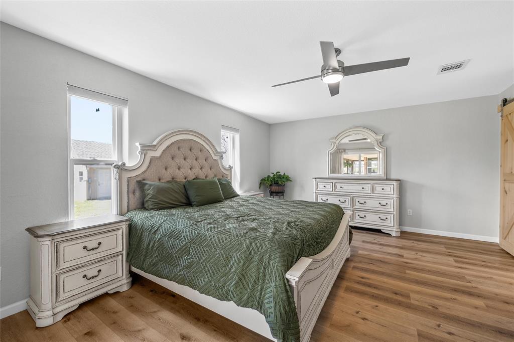 107 South Old Robinson Road Robinson, TX 76706 - Photo 18 of 39 Bedroom with a barn door, light wood finished floors, ceiling fan, and multiple windows
