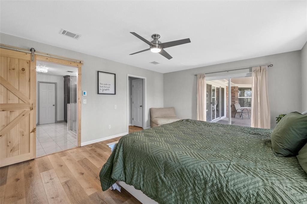107 South Old Robinson Road Robinson, TX 76706 - Photo 19 of 39 Bedroom featuring wood finished floors, a barn door, access to outside, and ceiling fan