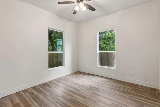an empty room with wooden floor and windows