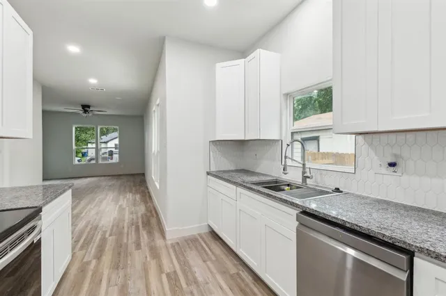 a kitchen with granite countertop a sink stove and cabinets