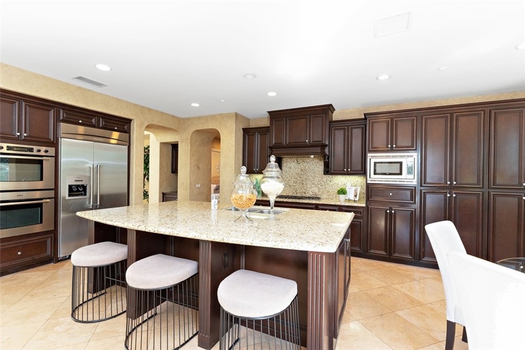 a kitchen with stainless steel appliances granite countertop a sink a stove a dining table and chairs