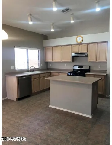 a kitchen with stainless steel appliances a sink a stove a microwave a center island and cabinets