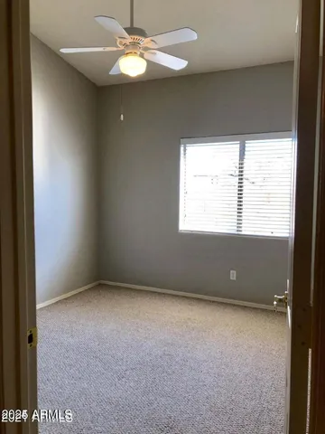 an empty room with a window and a fan