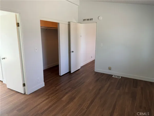 a view of an empty room with wooden floor and closet