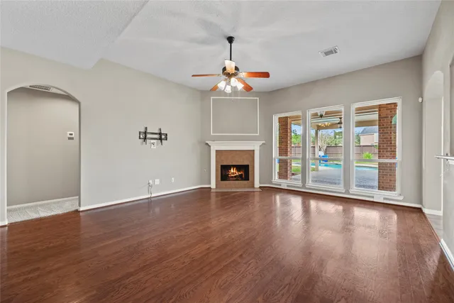 a view of an empty room with wooden floor fireplace and a window