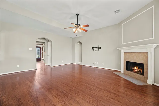 a view of an empty room with wooden floor fireplace and a window