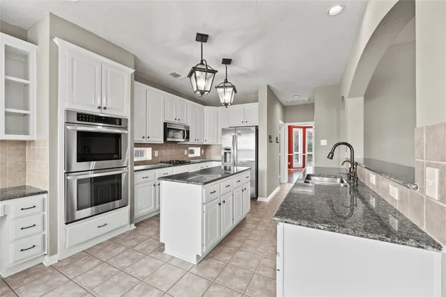 a kitchen with granite countertop a center island and stainless steel appliances