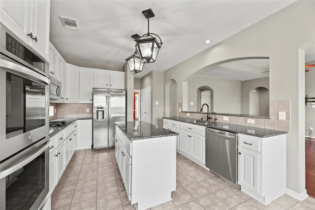 a large kitchen with cabinets a sink and stainless steel appliances