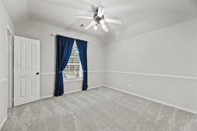 a view of an empty room and chandelier fan