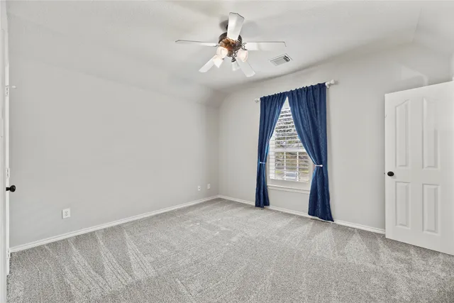a view of an empty room and chandelier fan