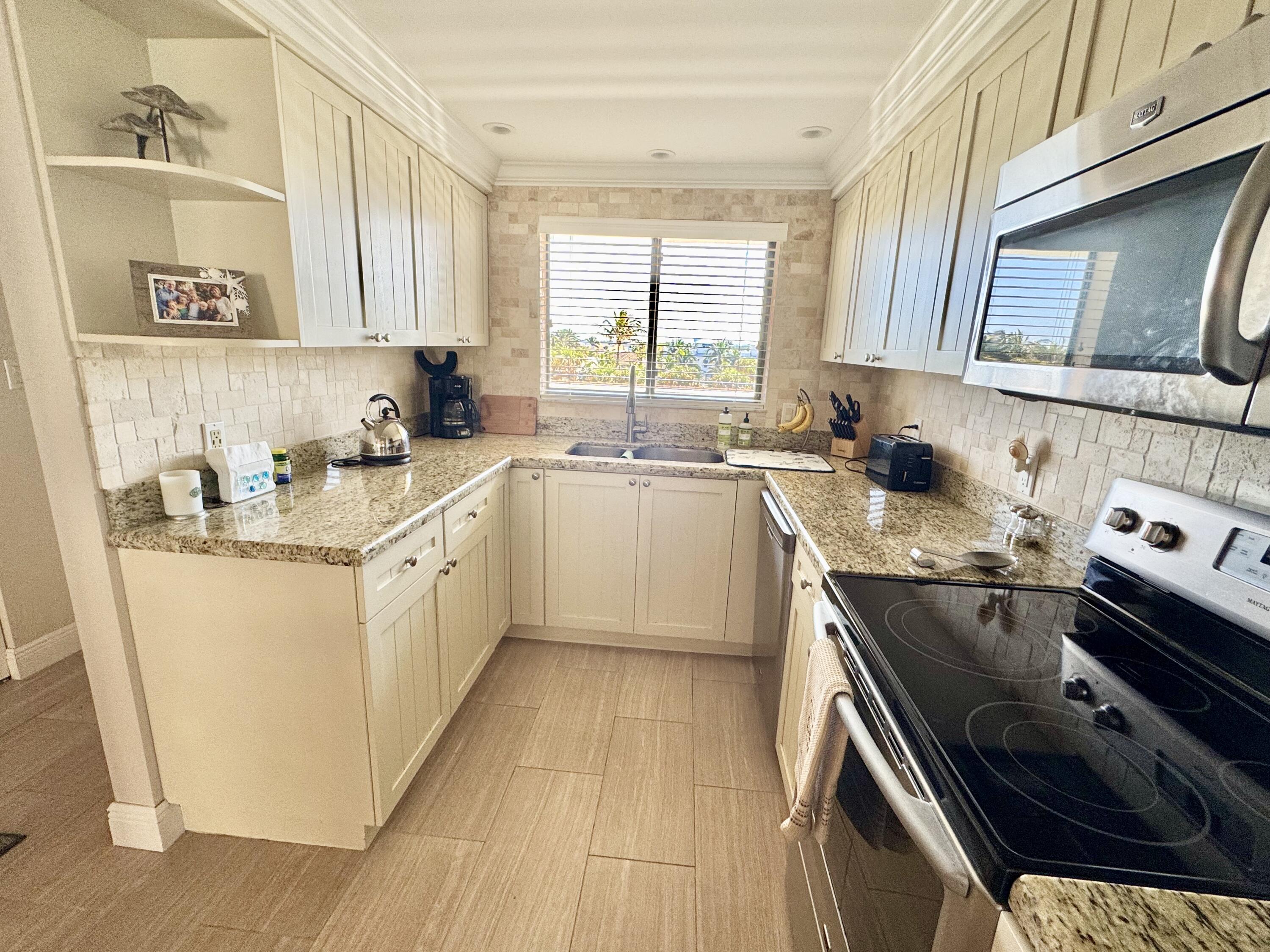 420 Celestial Way, Unit 403 Juno Beach, FL 33408 - Photo 20 of 25 a kitchen with a sink stove top oven and cabinets