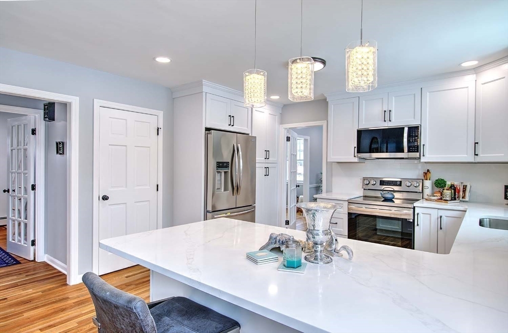 3 Pinetop Road Barrington, RI 02806 - Photo 14 of 38 a kitchen with stainless steel appliances kitchen island granite countertop a refrigerator a stove a sink a dining table and chairs with wooden floor