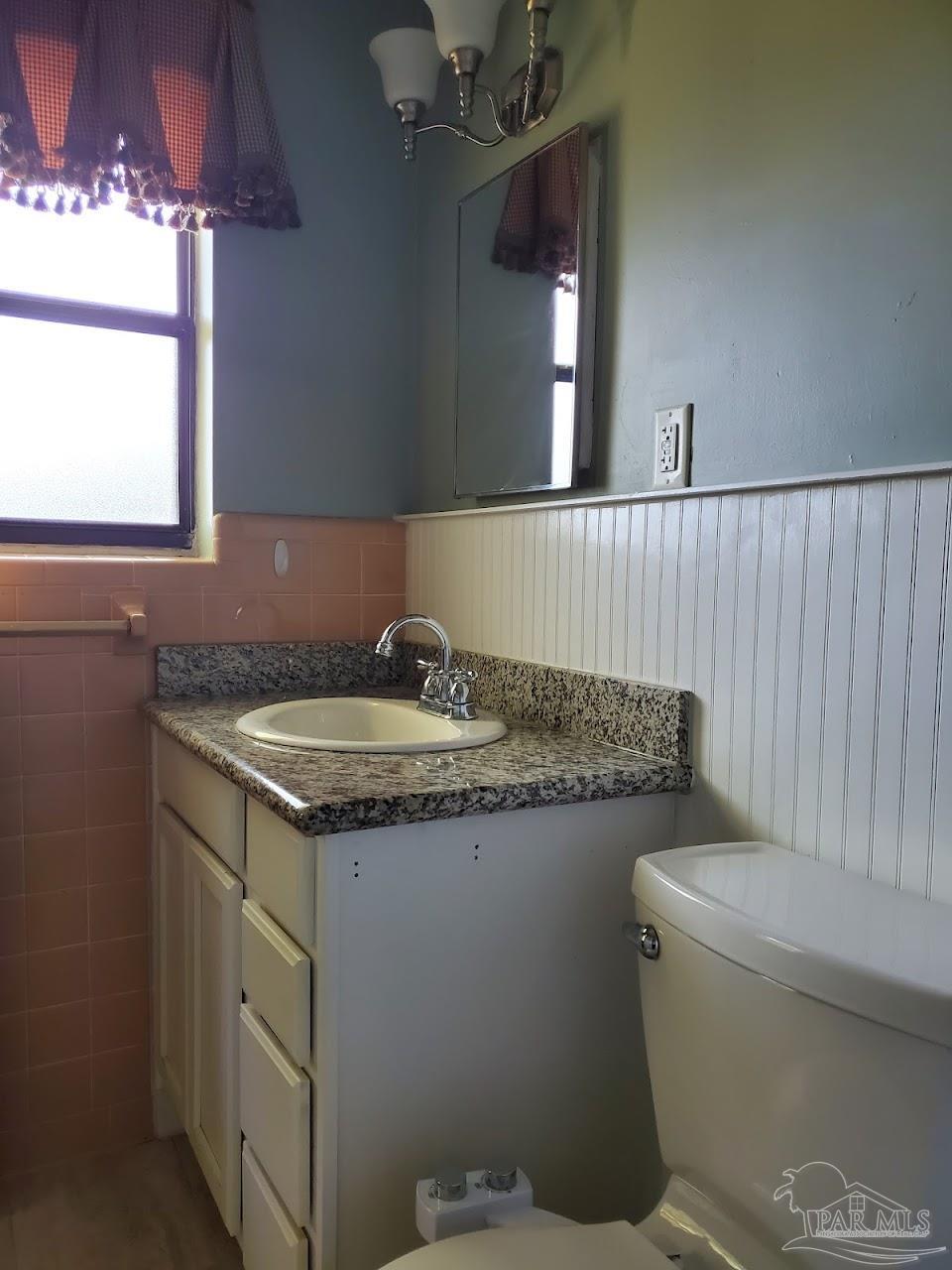 233 Cherokee Trail Pensacola, FL 32506 - Photo 27 of 36 a bathroom with a granite countertop toilet a sink and a mirror