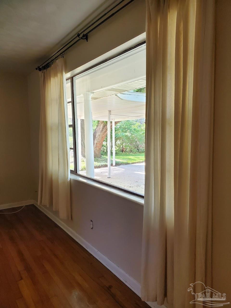 233 Cherokee Trail Pensacola, FL 32506 - Photo 4 of 36 a view of an empty room with wooden floor and a window