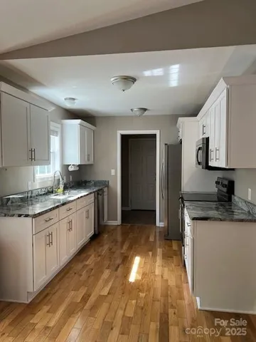 a kitchen with granite countertop a sink cabinets stainless steel appliances and a counter top space