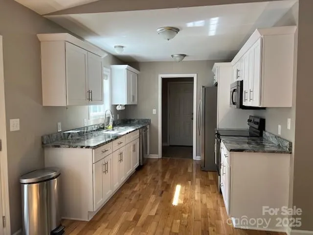 a kitchen with granite countertop a sink stove and refrigerator