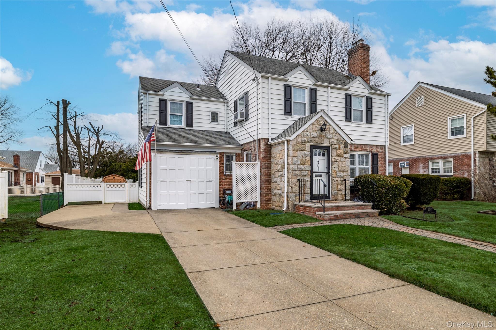135 Chestnut Street Lynbrook, NY 11563 - Photo 2 of 18 a front view of a house with a yard and garage