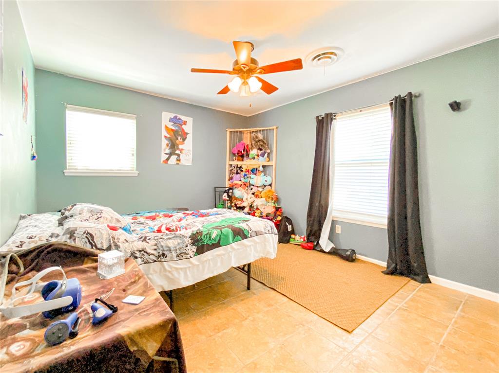 4301 Caprock Road Abilene, TX 79606 - Photo 13 of 29 Room featuring light blue walls, two windows with blinds, a ceiling fan with light fixture, and light-toned tile flooring