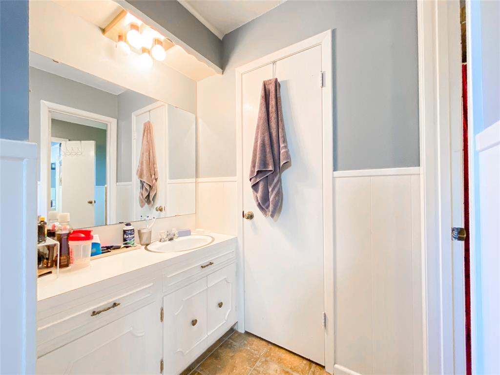 4301 Caprock Road Abilene, TX 79606 - Photo 19 of 29 Bathroom vanity featuring a white countertop with integrated sink, white cabinetry, and a full-width mirror