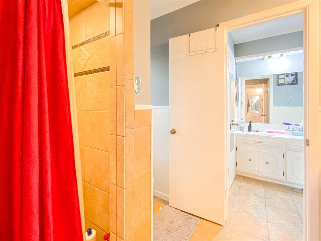4301 Caprock Road Abilene, TX 79606 - Photo 20 of 29 Shower enclosure with neutral-toned tiled walls, featuring decorative accent tiles
