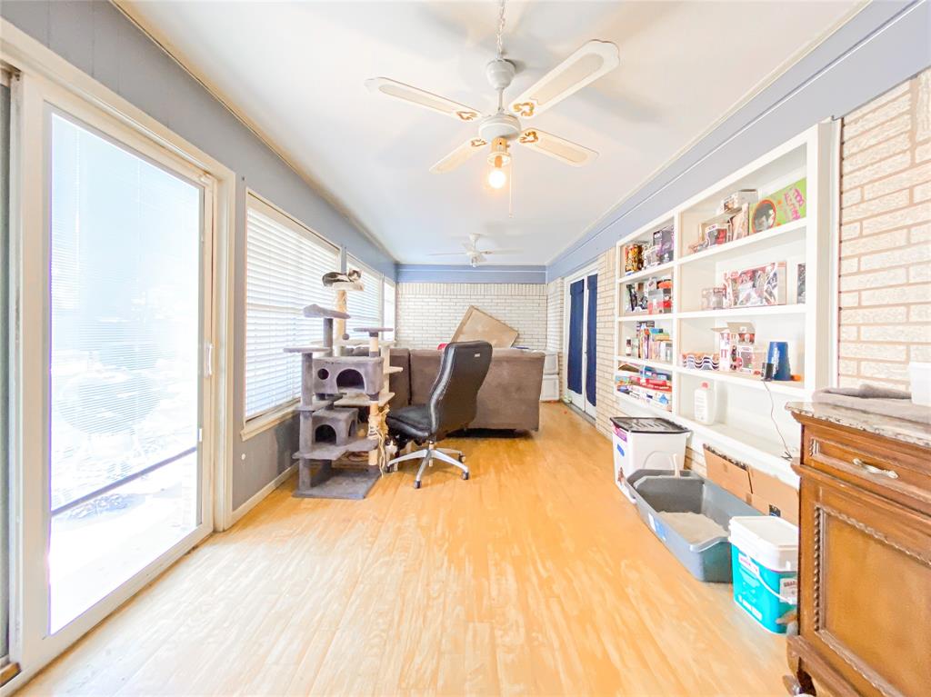4301 Caprock Road Abilene, TX 79606 - Photo 23 of 29 Bright room featuring wood-finish flooring, a full wall of built-in shelving, white brick accent walls, and ceiling fans