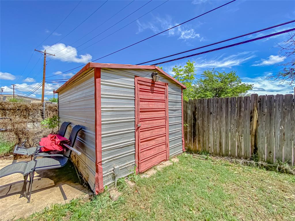 4301 Caprock Road Abilene, TX 79606 - Photo 26 of 29 Corrugated metal shed with a red door and a single exterior light fixture
