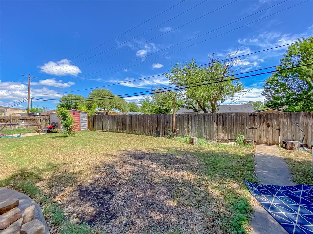 4301 Caprock Road Abilene, TX 79606 - Photo 29 of 29 Expansive backyard space featuring a wooden privacy fence, a concrete walkway, and a storage shed