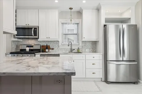 a kitchen with white cabinets and stainless steel appliances