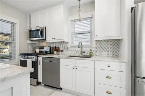 a kitchen with granite countertop white cabinets and stainless steel appliances
