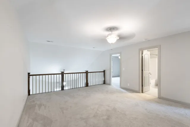 a view of an empty room with a chandelier fan