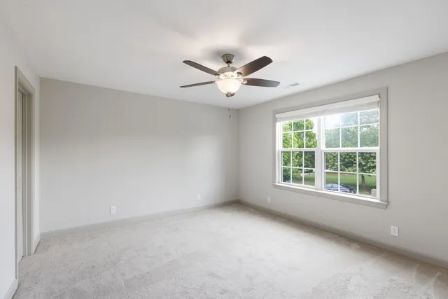an empty room with a window and a ceiling fan