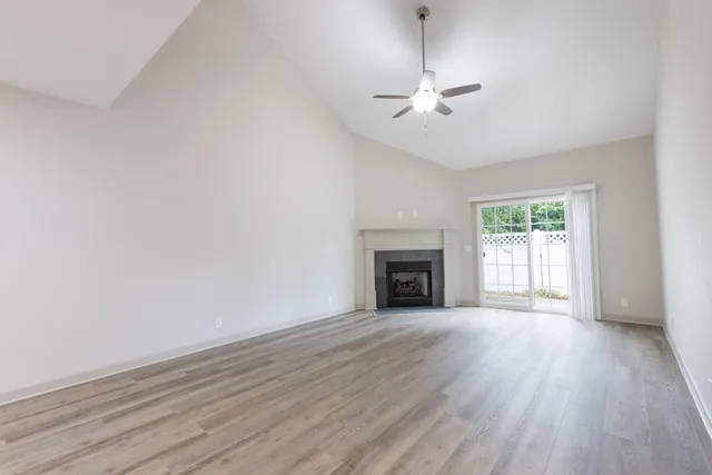 an empty room with wooden floor fireplace and windows