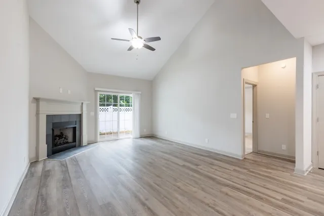 an empty room with wooden floor fireplace and windows