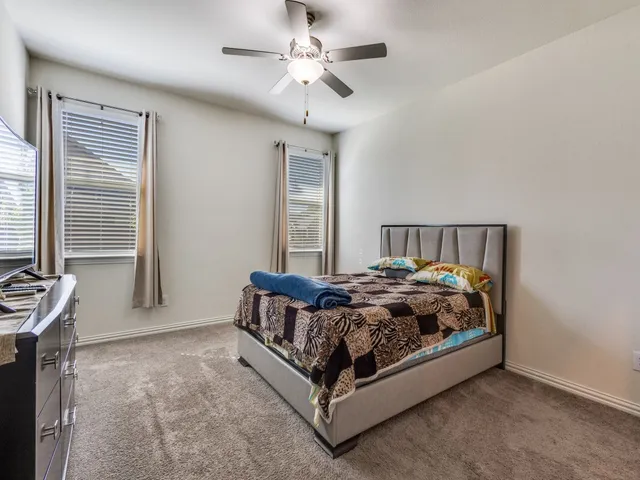 a bed sitting in a bedroom next to a window and a chandelier