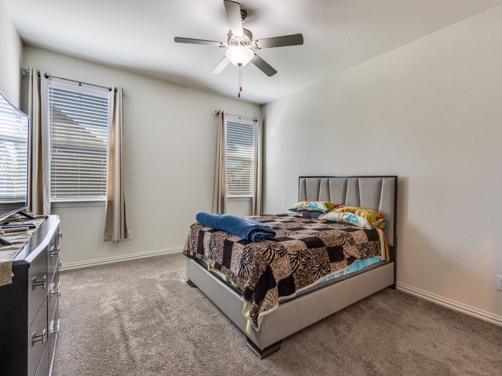 302 Pepperbark Avenue Princeton, TX 75407 - Photo 8 of 12 a bed sitting in a bedroom next to a window and a chandelier