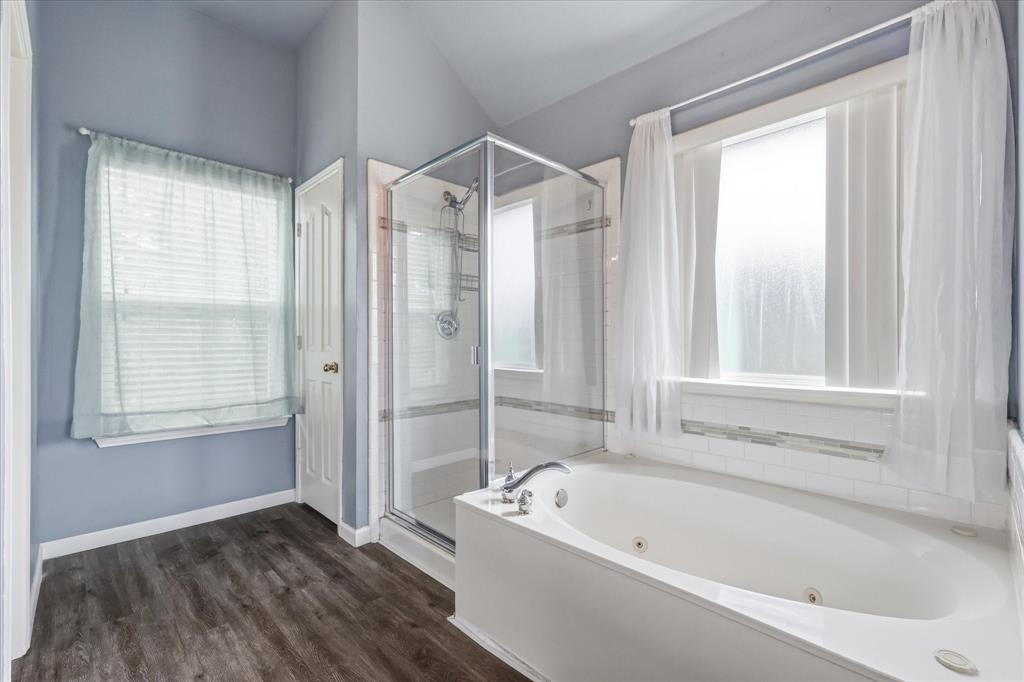 4545 Ridgepointe Drive The Colony, TX 75056 - Photo 26 of 37 Bathroom featuring a corner glass-enclosed shower, a jetted soaking tub with a tiled surround, and wood-finish flooring