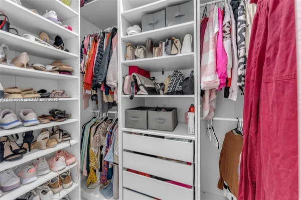a view of walk in closet with clothes and shoes