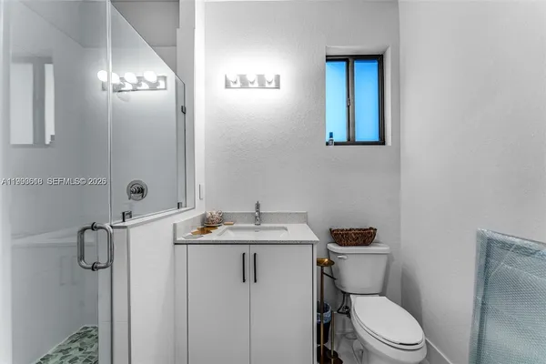 a bathroom with a granite countertop sink mirror vanity and toilet