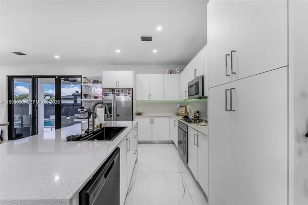 a kitchen with stainless steel appliances granite countertop a sink refrigerator and cabinets