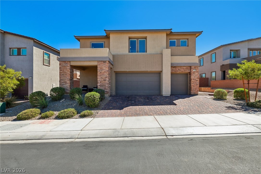 194 Viento Ridge Street Henderson, NV 89012 - Photo 1 of 72 A striking modern facade pairs warm stucco with textured stone columns and a paved driveway.